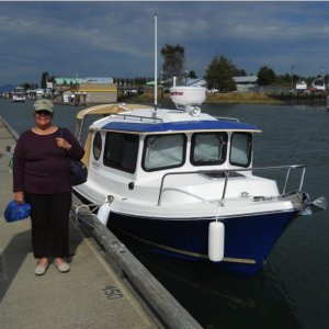 Betty and Our Marinaut at La Conner.  Please take a look at the front, starboard window.  It is so wide, that I can easily hang out the window to set the midships fender and docking line to the dock cleat.  It's not just my arm -- I can comfortably hang the entire upper part of my body out the window to set the line and fender.  This has greatly made docking easier.  What a great design!

Shown also are the privacy, snap-on canvas curtains in the front windows