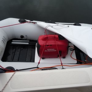 5. In rainy weather I put the 3-1/2" thick foam seating pad that I use normally in the dingy, under the 1/4" white plastic sheet the generator sits on to give it more distance off the bottom of the dingy. The white tarp bungy cord's on above the generator to protect it from the rain.