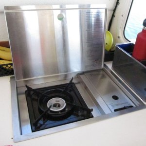 Media 'Princess butane drop-in stove, flat stainless lidded version (other version has wooden cutting board that sits on top).' in album 'Sink cover board while varnishing.  I made a similar one (sans hole) for the cutout where the Wallas used to be.  It's surprisingly handy to be able to remove it to work on things (wiring etc.) under the galley, although I may eventually replace the whole galley counter and if so will likely make it a solid piece except for the sink cutout.'