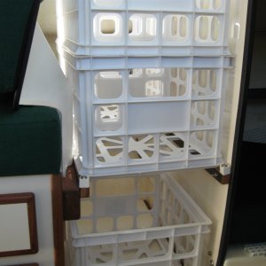 Port forward seat leg space with 5 storage crates.  2x2 stacked on top.  1 under with space behind.