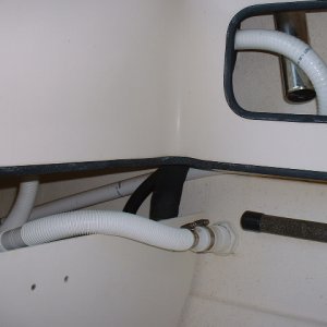 Water from the pump flows through the hose that bends by that rod holder and enters the tank. The other hose is the drain that is continuously discharged overboard.