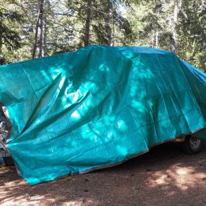 The $20 plastic tarp thrown over the boat.  Measure the amount it hangs down too much front and rear and cut a dart in the middle.  Piece it back together with duct tape.