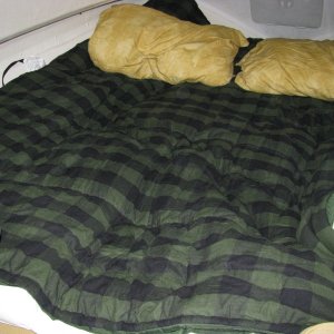 Fully extended berth showing head-first sleeping arrangement. Shown are two, queen size pillows.   We bought two flannel sleeping bags, good to 40 degrees, for $136 at LL Bean.  We unzipped them, using one for the bottom, which sat on top of our fiberbed topper, and the other was used as a comforter.  Overall, this sleep space is roughly 6 feet long by 5 feet wide, with a slight decrease to 4.5 feet at the bulkhead.  We slept better is this berth then we did at home.  9/26/12 comment.  This berth is a lot larger than one would think.  I can sleep across the bunker once past the bulkhead.  The only issue with sleeping toward the bow is the deck is close to one's head, but that's OK after awhile, since you have a cavernous view of the cabin from that perspective as well as having the hatch overhead.  Another thing that should be considered is that if any of you suffer from heartburn like I do, you know that it is infinitely preferable for your head to be higher then your feet.  Sleeping with your head toward the bow achieves this.
