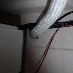 Shadows create an optical illusion, the wiring and cables are actually separated from the exhaust by a good 4 inches.  The exhaust port also has a guard tacked to the top of it so really it's impossible for the wires to come into contact even if somehow they fell or sagged.