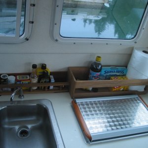 (CheckRaise) A galley storage solution. The teak rail and standalone shelf unit are simply velcroed in.