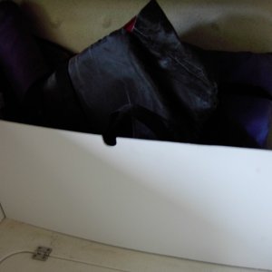 Simple shelf. Cut two slits in the starboard at an angle.This allows the board to lean out at the top for more room and still allow the hatch below to open. Notch out 1/8" ply for the table leg when dropped to bed configuration. Then slide in wood. This holds a bunch of bulky stuff such as PFD's, boat cushions,frisbee's, dogs water toys and a beach shade tent.  Two swim noodles lay fore and aft across the top. Ventalation is such that damp items can still air out. Want to reconfigure to a stock boat?  Just lift out the board.The factory carpet still fits underneath.