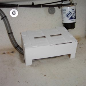 My first bilge cover was so heavy duty it could double as a trailer chock block. Now I have to put the boat on a diet. Check your trash can for one of these. This is one of those boxes that tangerine oranges come in. Ultra-light weight yet strong enough to protect the pump. My spare parts box is a tackle box that rides on top of the cover. Then the space gets filled with camping stuff.