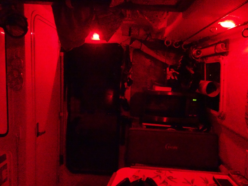 Looking aft, red lights above door, and in the light fixture over the aft dinette seat (white there for reading also)   One of the two cabin door screens is in place.