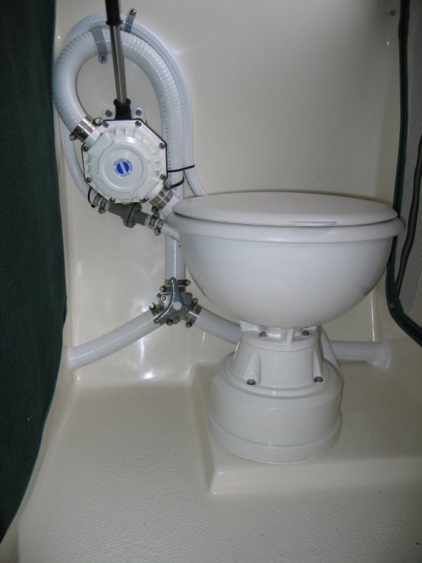 (Sea Skipper) Lavac vacuum head with manual waste discharge pump.  2nd Y valve (hidden behind head) is used to route suction line to a bilge strainer mounted below cabin steps for use as an emergency bilge pump.  Head is mounted at a comfortable height on an 8? PVC pipe cap.