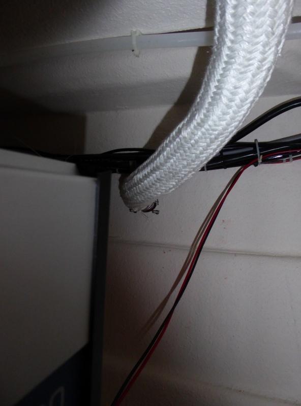 Shadows create an optical illusion, the wiring and cables are actually separated from the exhaust by a good 4 inches.  The exhaust port also has a guard tacked to the top of it so really it's impossible for the wires to come into contact even if somehow they fell or sagged.