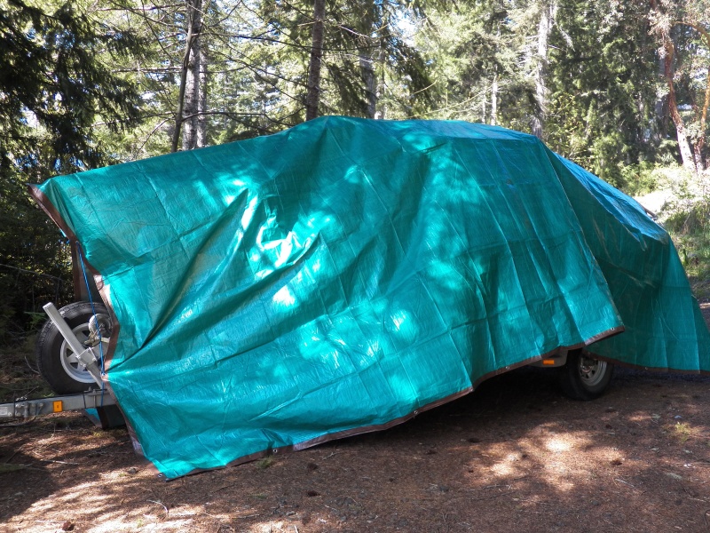 The $20 plastic tarp thrown over the boat.  Measure the amount it hangs down too much front and rear and cut a dart in the middle.  Piece it back together with duct tape.